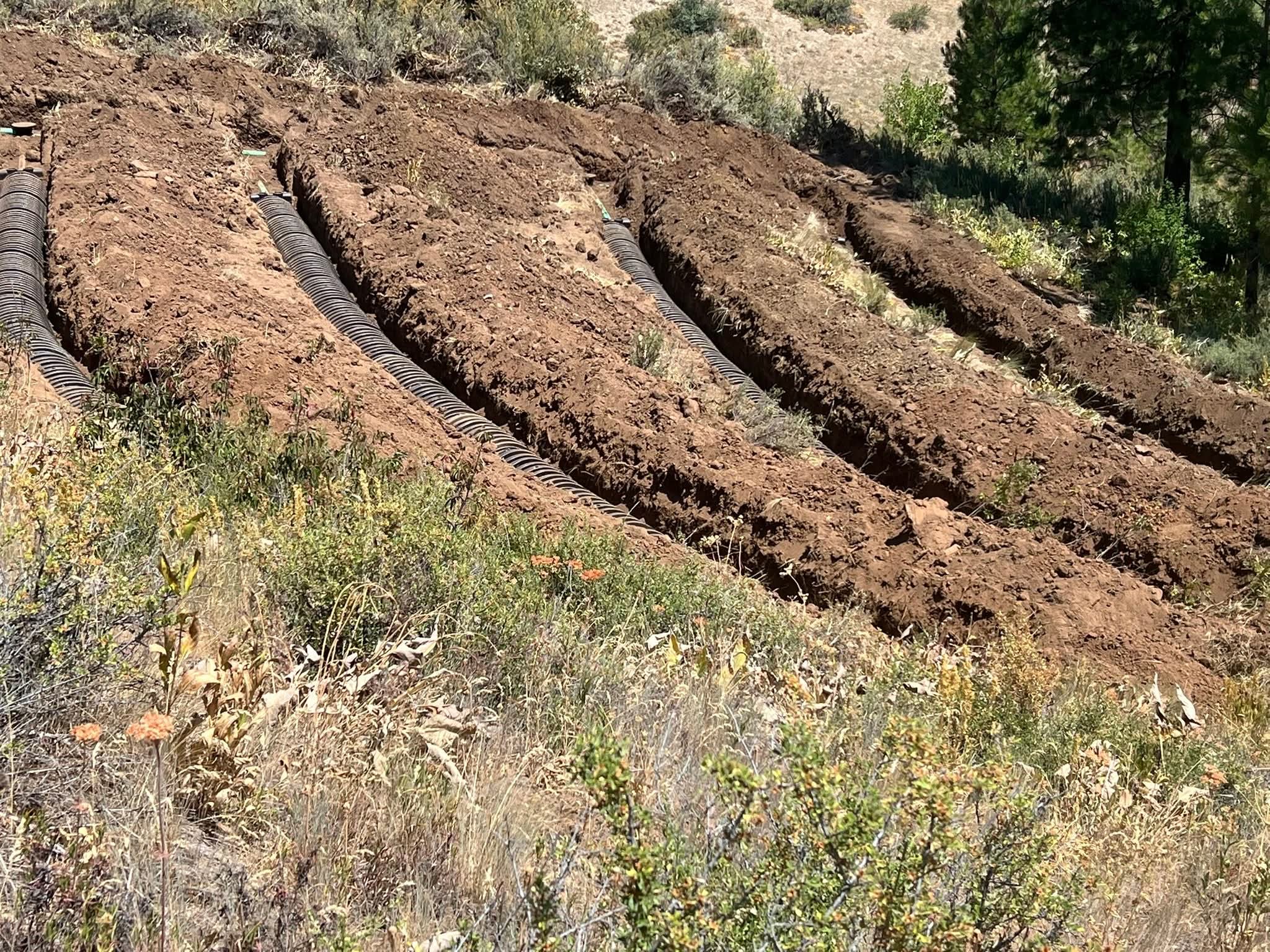 Complex drain field installation with parallel corrugated pipes laid in trenches on a hillside