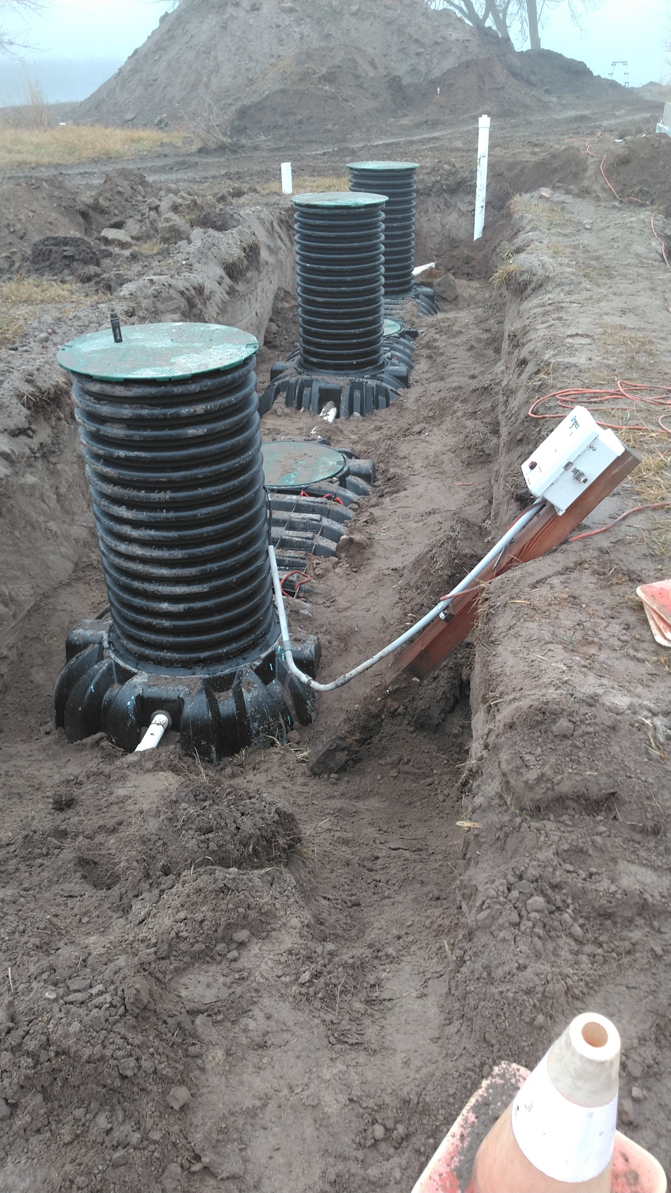 Septic system installation with corrugated risers and piping in excavated trench