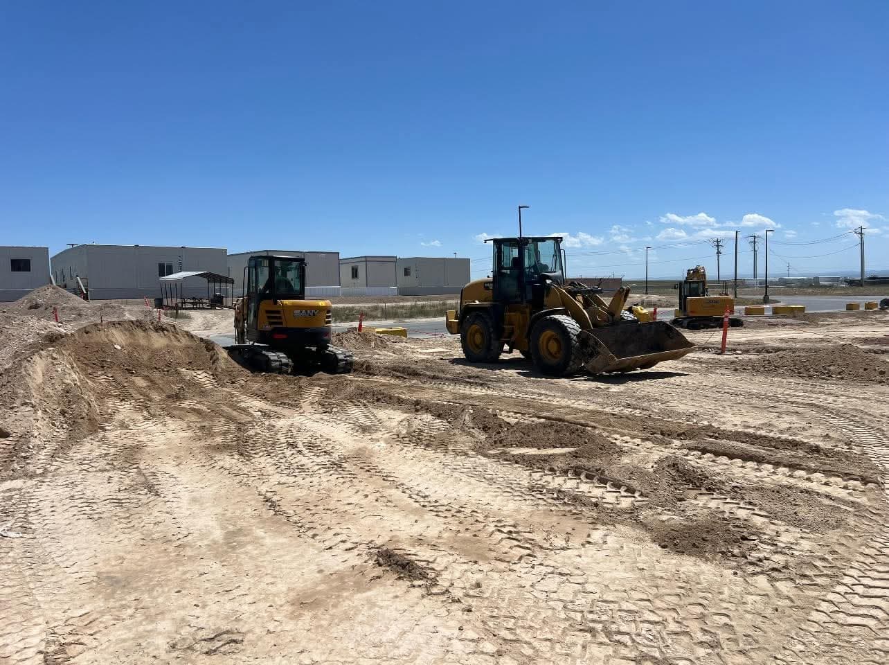 SANY excavator and wheel loader clearing and grading a commercial construction site